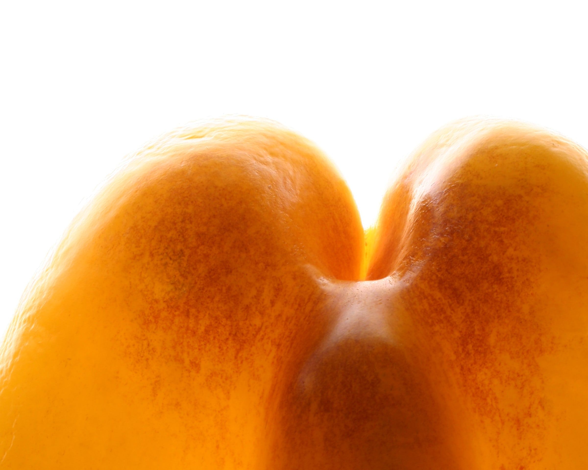 The backlit base of an orange bell pepper against white